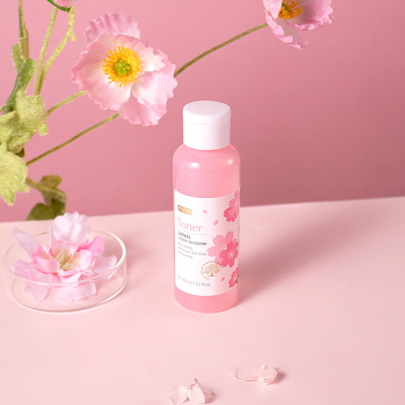Cherry blossom hydrating lotion displayed with pink flowers against a soft pink background.