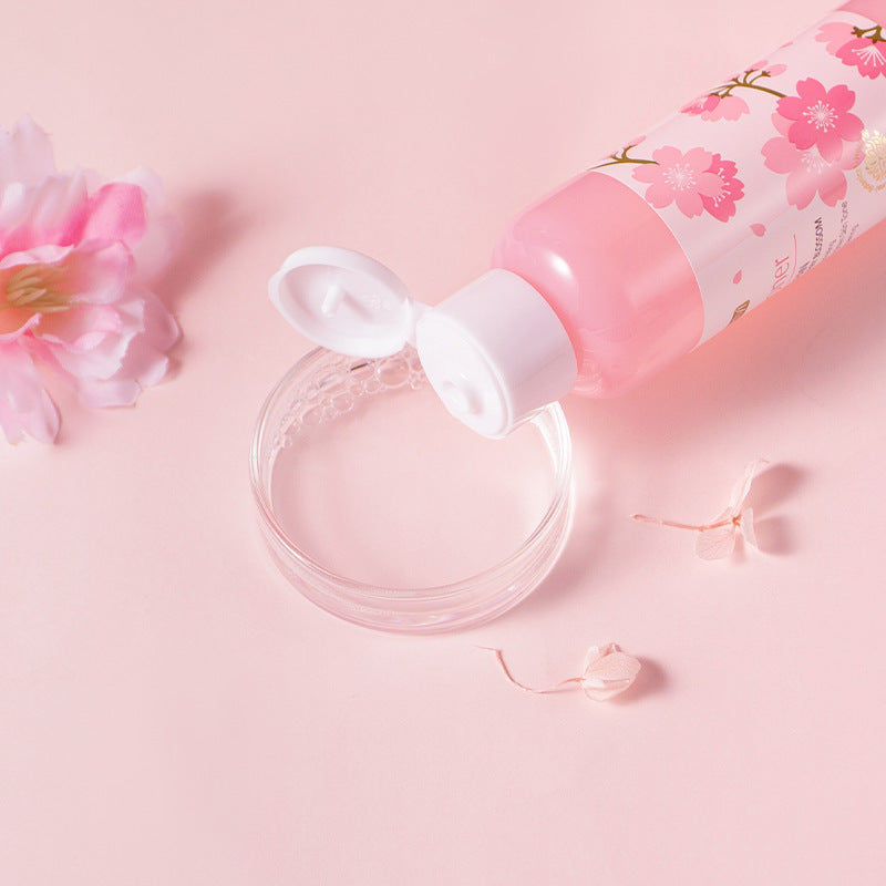 Cherry blossom hydrating lotion bottle with floral design, placed on a pink background alongside cherry blossom petals.